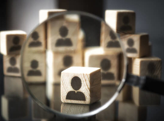 magnifying glass focused on a group of wooden blocks that each have an anonymous person icon on them