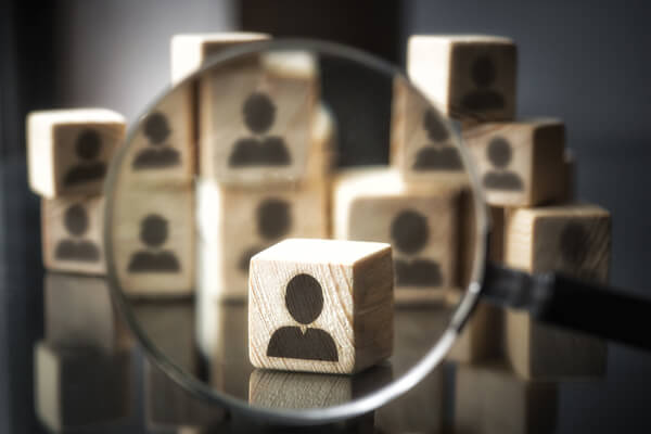 magnifying glass focused on a group of wooden blocks that each have an anonymous person icon on them