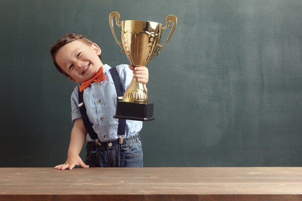 young boy in business clothing holding a trophy