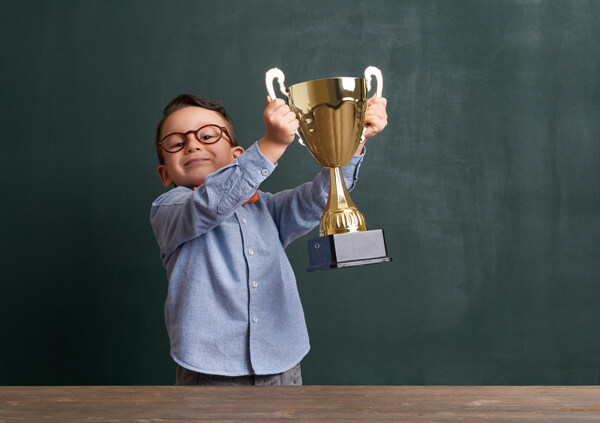 young boy in business clothing holding a trophy