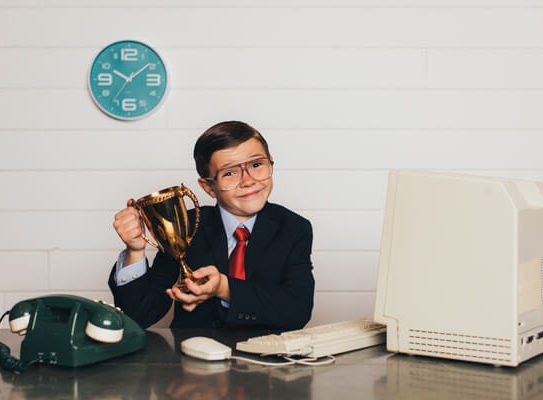 young boy in business clothing holding a trophy