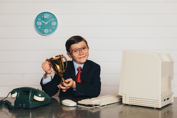 young boy in business clothing holding a trophy