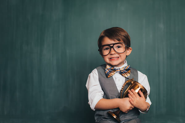 young boy in business clothing holding a trophy