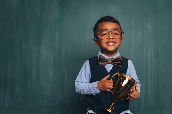 young boy in business clothing holding a trophy