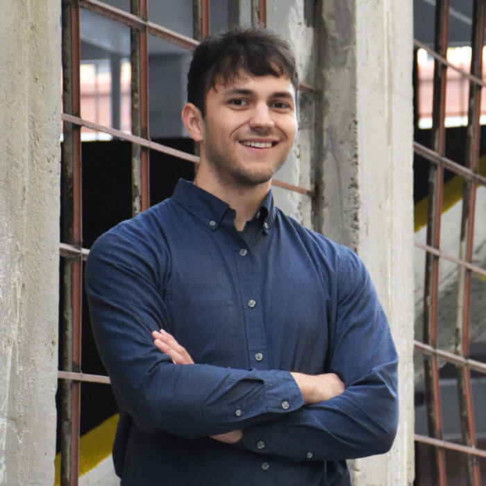Cody Meek smiling and standing in front of industrial building