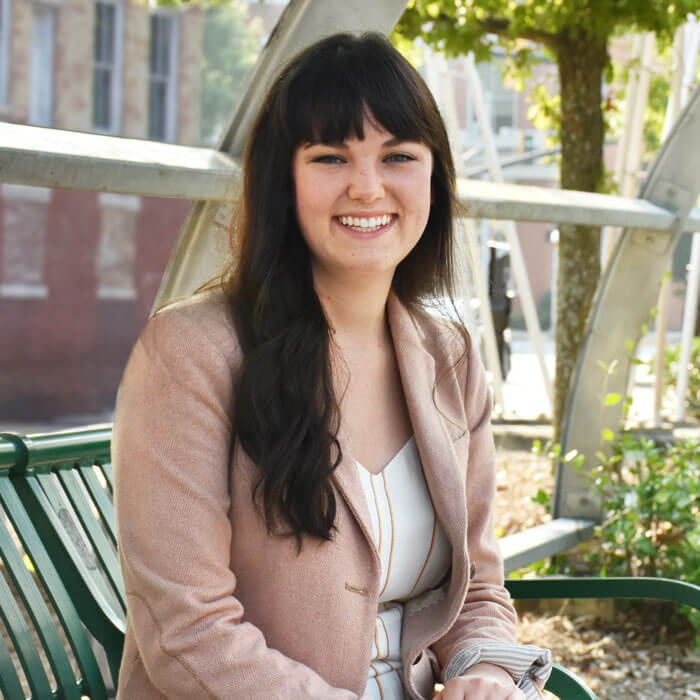 Katy Ward smiling and sitting on bench in a Downtown Macon park