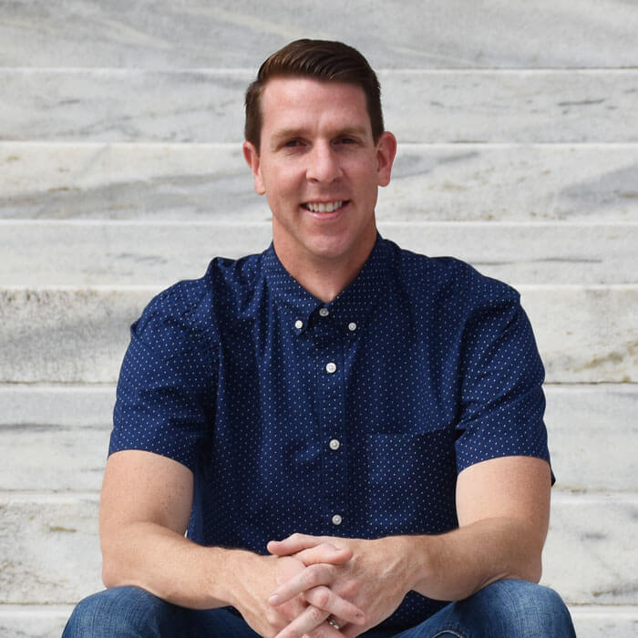 Matt Evans smiling and sitting on marble staircase