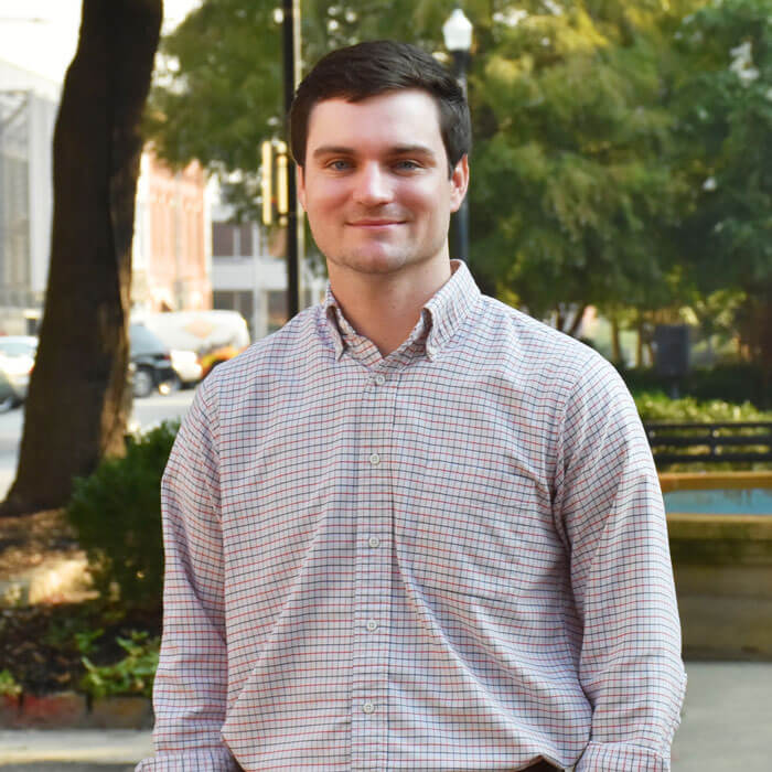Reece Freel smiling and standing in front of fountain in Downtown Macon