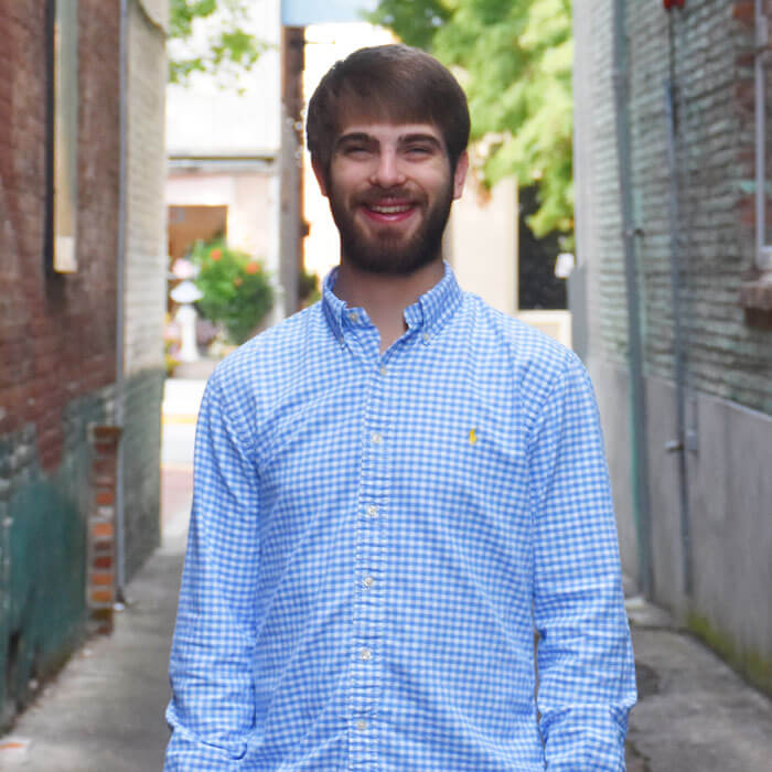 Ryan Knapp smiling and standing in brick alleyway