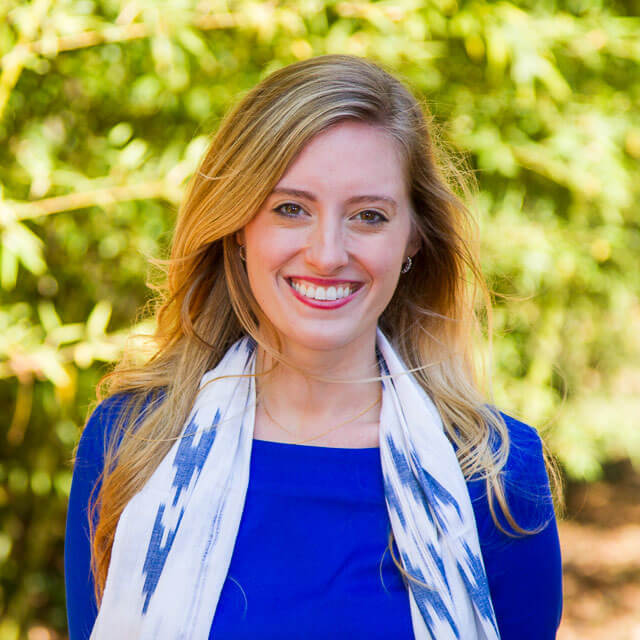 Sarah Howard smiling and standing in front of greenery