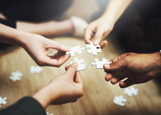 4 puzzle pieces, each being held by a person sitting on the floor