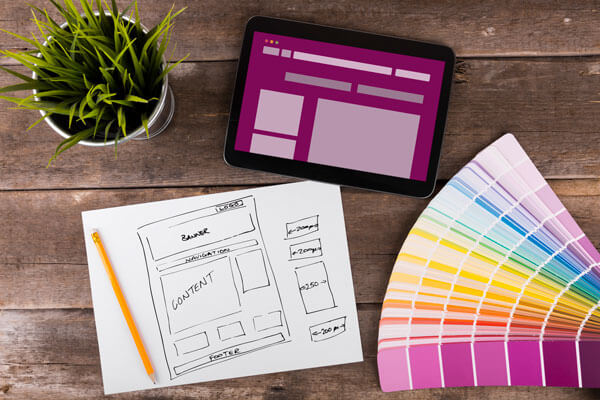 a mockup design, color swatch booklet, and tablet are placed on a table next to a plant