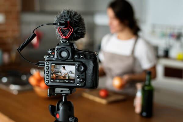 a DSLR camera is filming a woman preparing a recipe