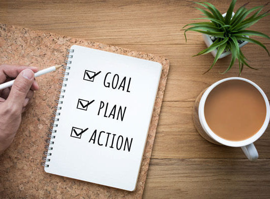 a notebook that says 'goal', 'plan', and 'action' on a table next to a cup of coffee