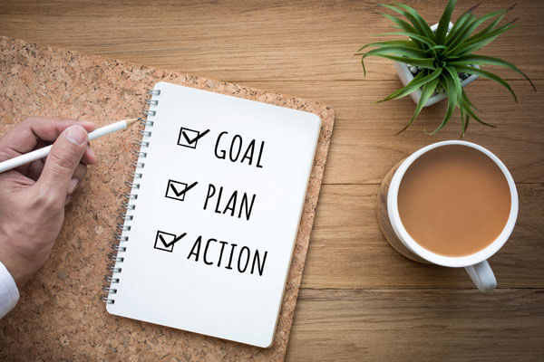 a notebook that says 'goal', 'plan', and 'action' on a table next to a cup of coffee