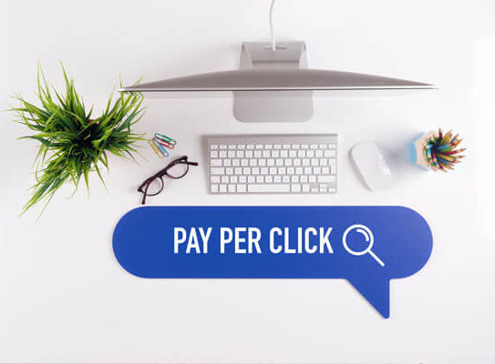 speech bubble with the words 'pay per click' in front of a desktop computer