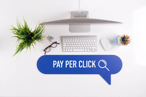 speech bubble with the words 'pay per click' in front of a desktop computer