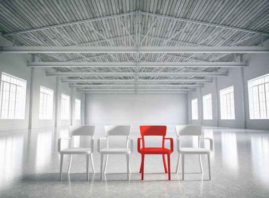 red chair in a group of white chairs in an empty room