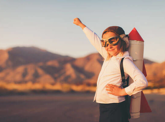 young girl wearing eye goggles and a rocket on her back in a mountainous desert