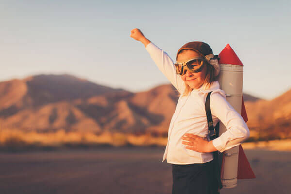 young girl wearing eye goggles and a rocket on her back in a mountainous desert