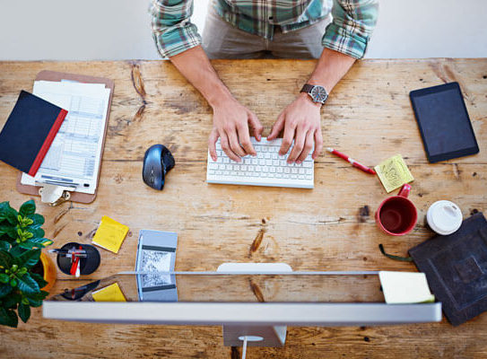 man sits at a table and uses a desktop computer