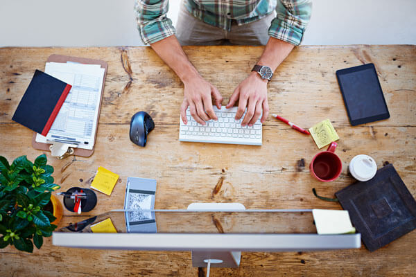 man sits at a table and uses a desktop computer