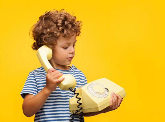 young boy holding a telephone with a cord and a dial