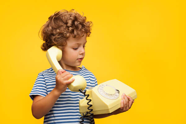 young boy holding a telephone with a cord and a dial