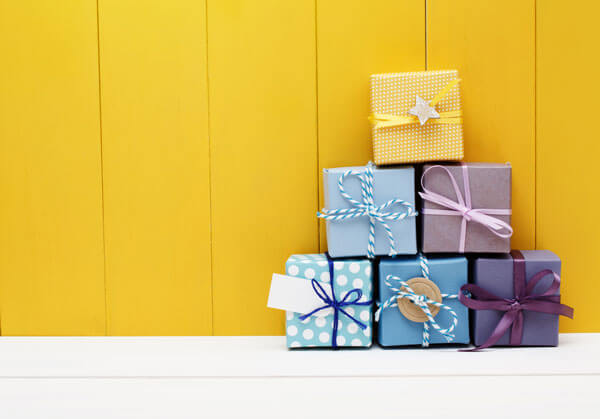 pile of christmas presents in front of a yellow background