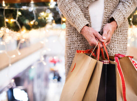 woman holds several shopping bags in a store with Christmas decorations