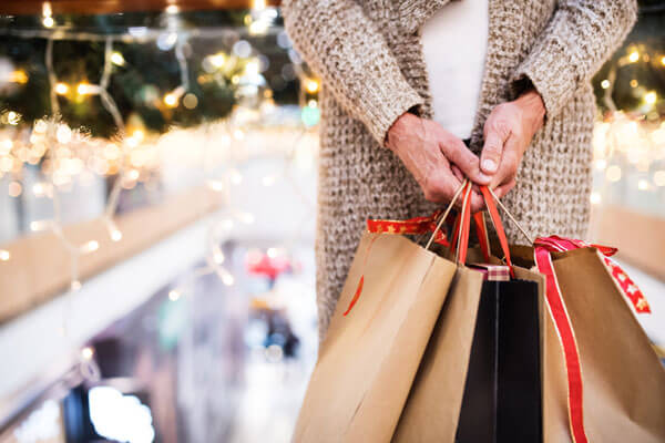 woman holds several shopping bags in a store with Christmas decorations