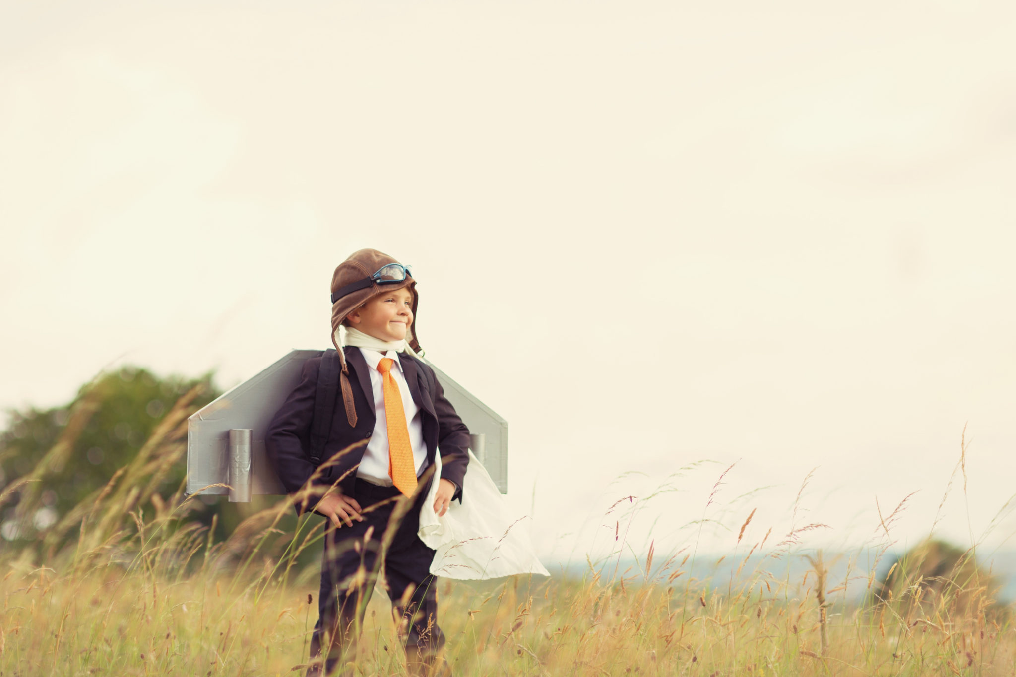 young kid in a suit standing triumphantly in a field