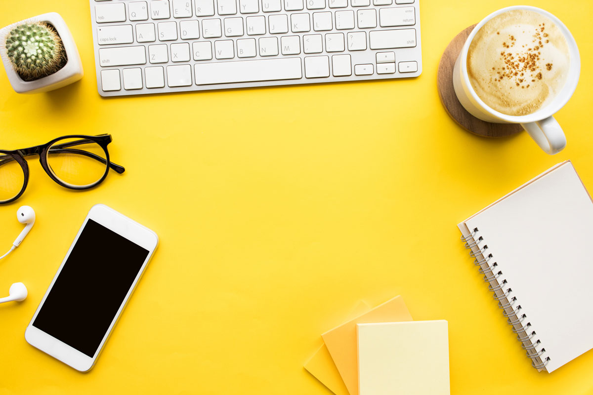 closeup shot of a desk with notebooks, a phone, and a computer