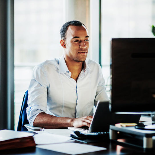 Young businessman typing on laptop in office