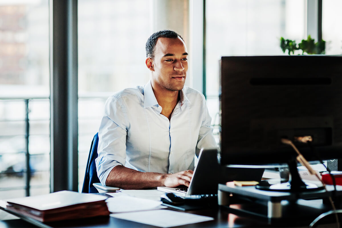 Young businessman typing on laptop in office