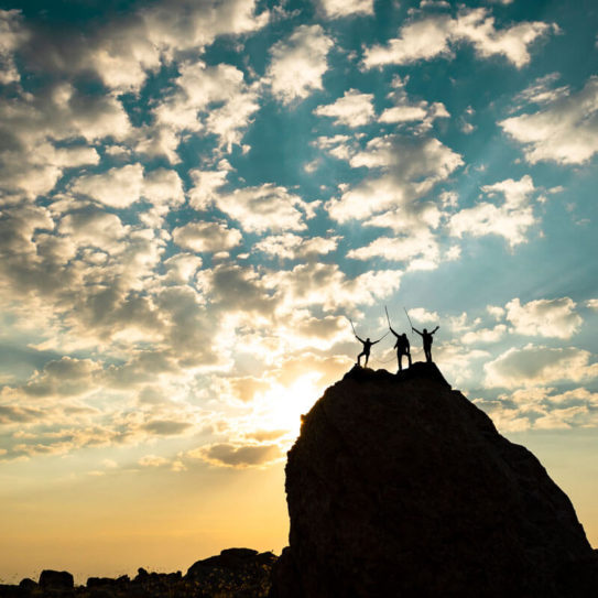 people triumphantly standing on top of a mountain