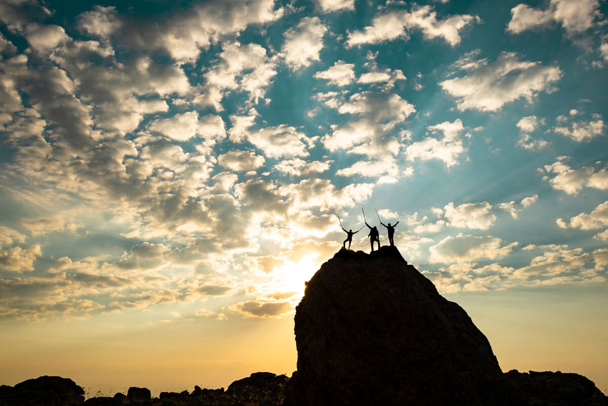 people triumphantly standing on top of a mountain