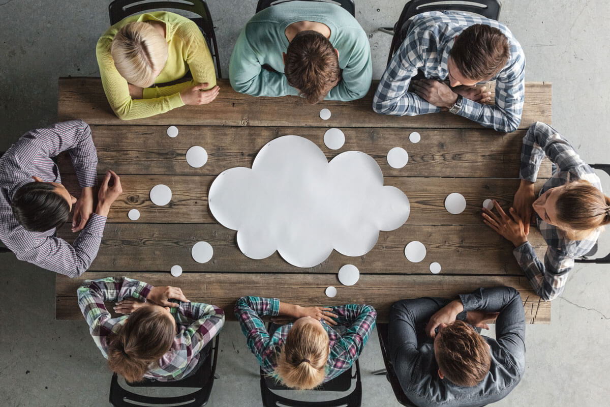 a group of young professionals sit around a table that has a paper speech bubble on it