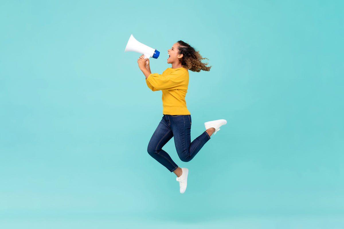 a young woman jumps and simultaneously screams into a megaphone