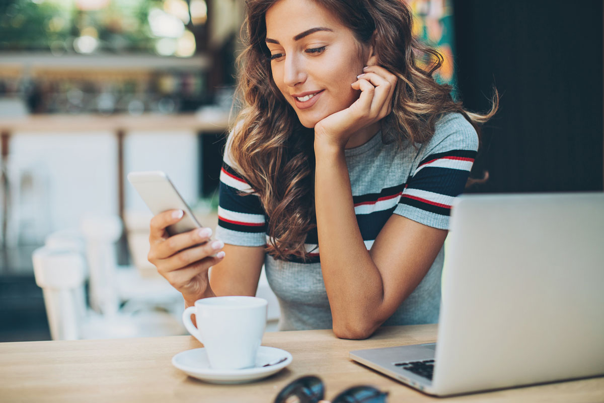 a young business owner looks pleased at the results shown on her phone