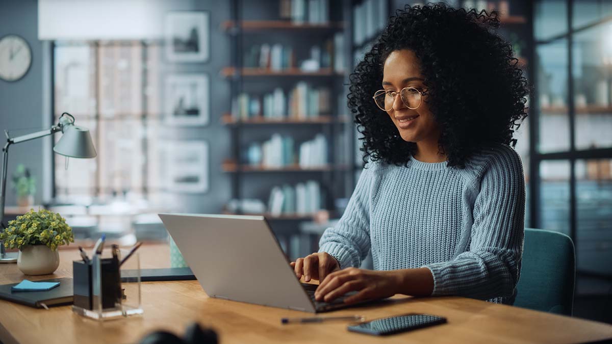 Female business owner Sitting at a Desk in a Cozy Living Room and Using Laptop Computer at Home.