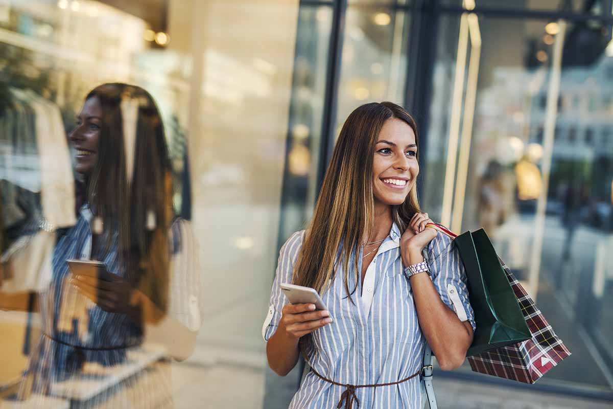 Woman checking smart phone in front of store window