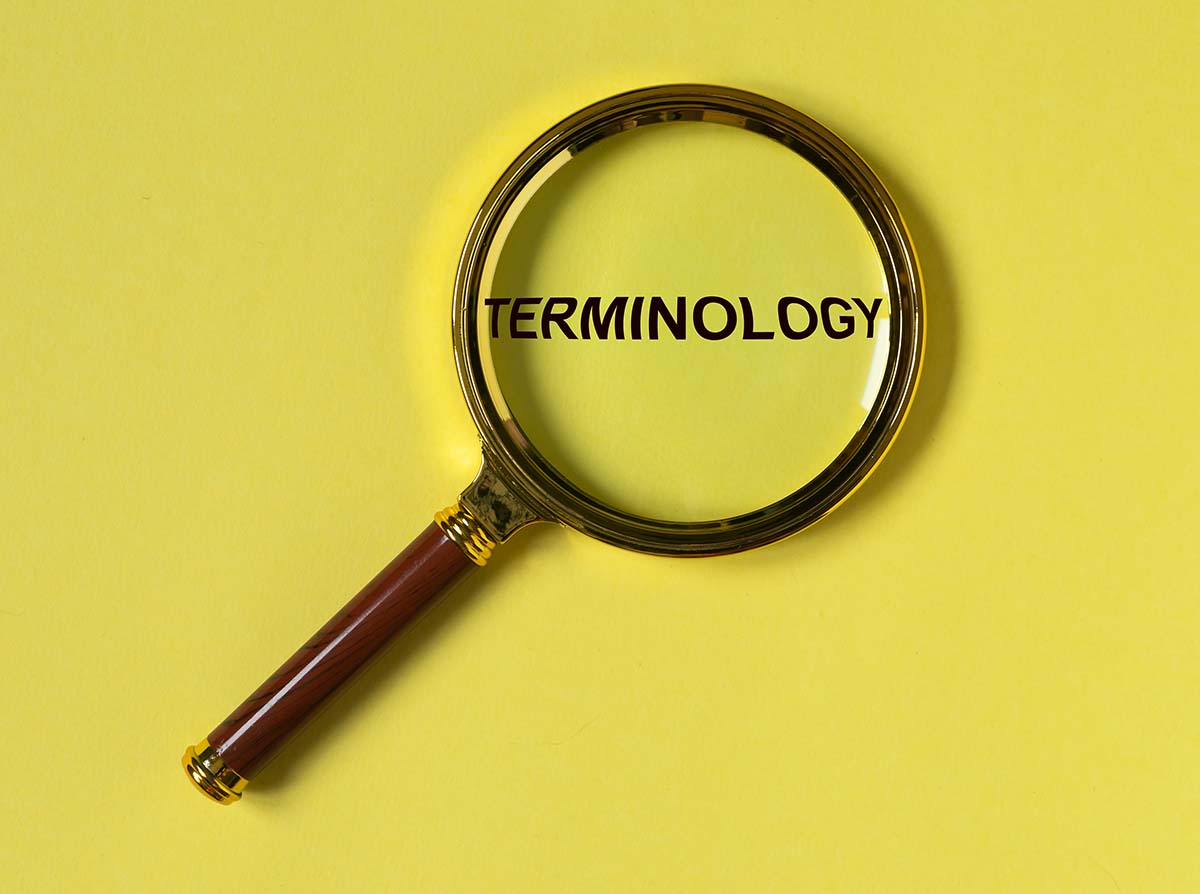 Terminology word through magnifier on bright yellow background, top view.