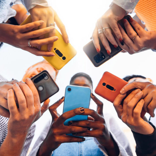 a group of people standing a in a circle and using their phones