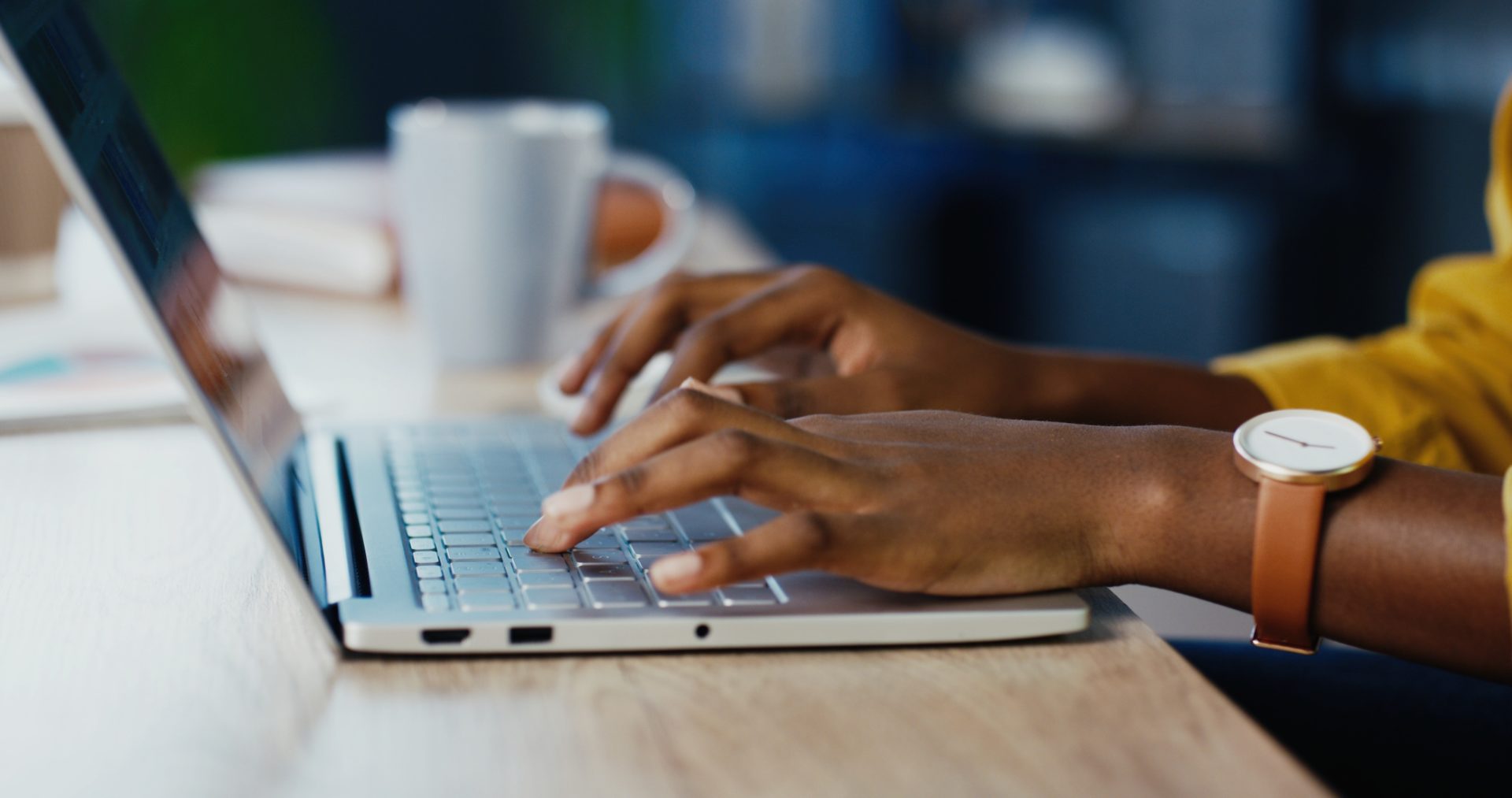 female hands typing on laptop while sitting at office desk indoors.