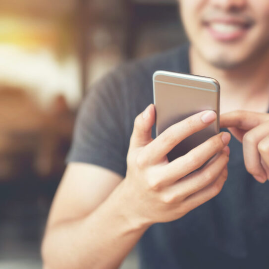 Happy male using smartphone at modern coffee shop