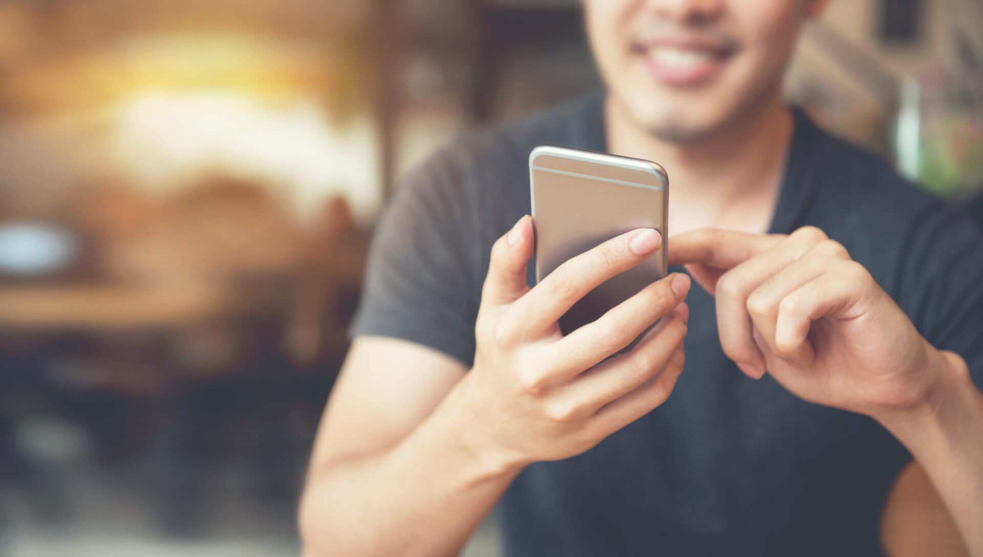 Happy male using smartphone at modern coffee shop