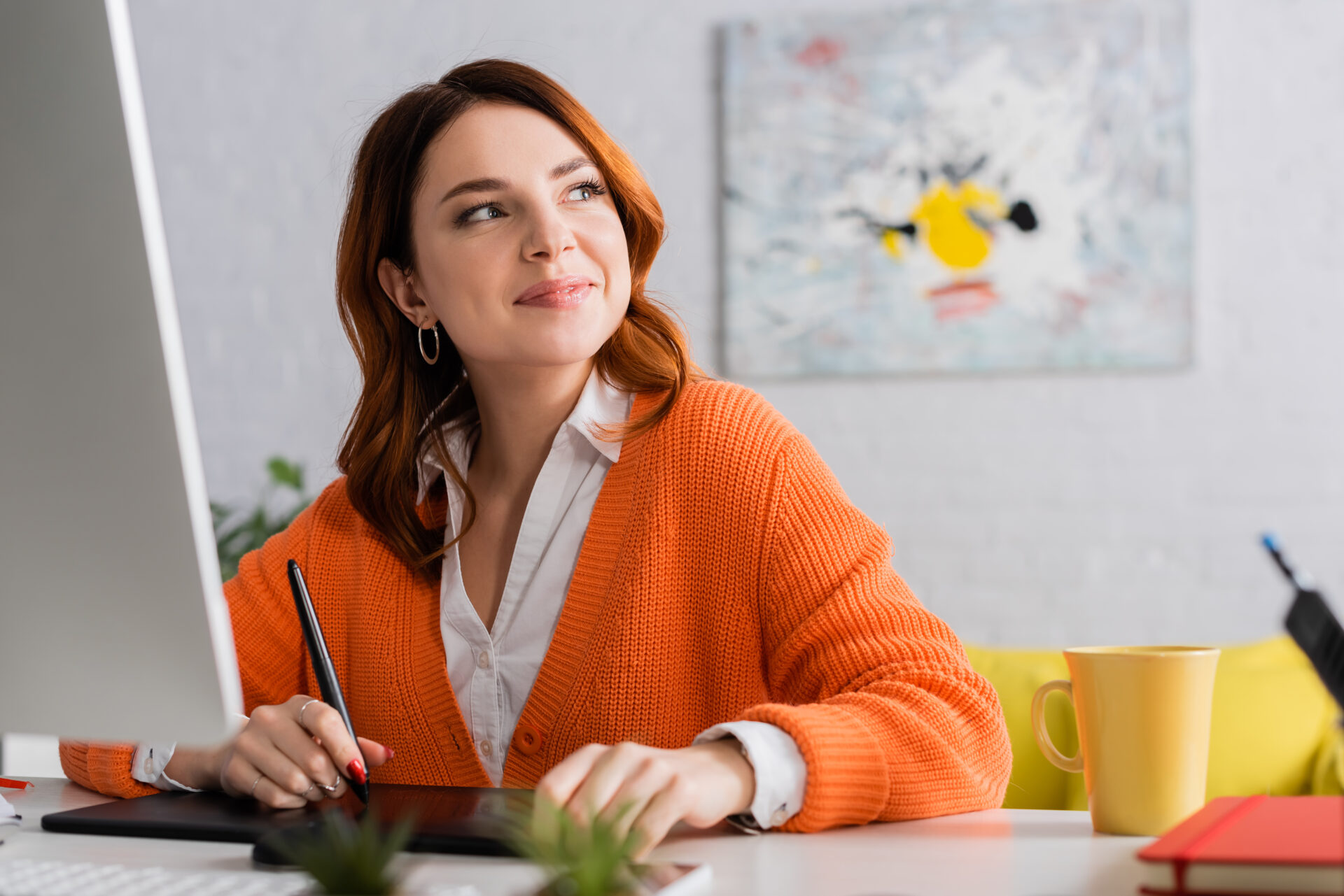 happy designer looking away while working on graphic tablet at home