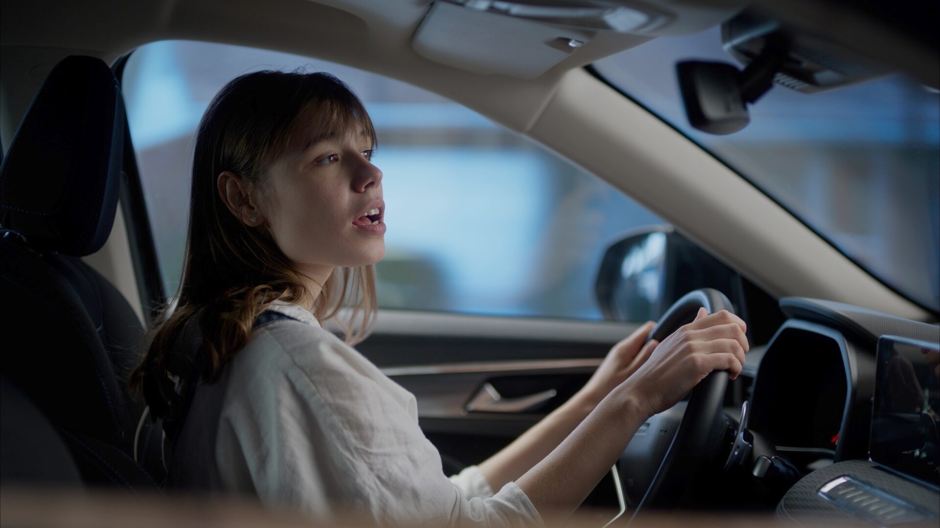 Caucasian female dancing and singing to her favorite song while driving the car during the suburbs neighborhood