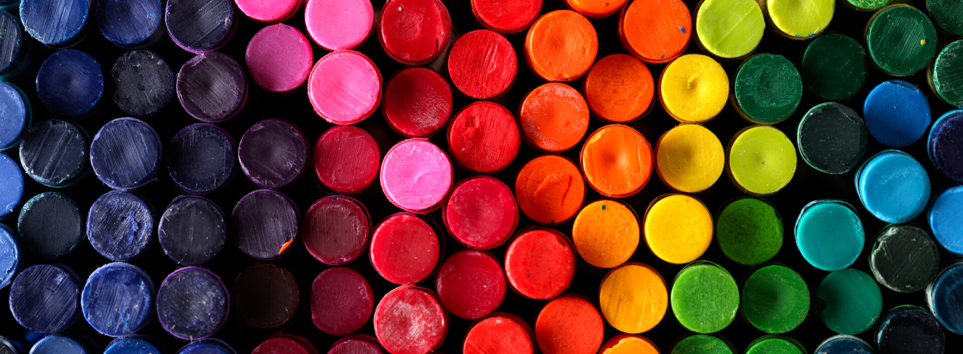 A collection of crayons, viewed from the end, creating a rainbow effect.